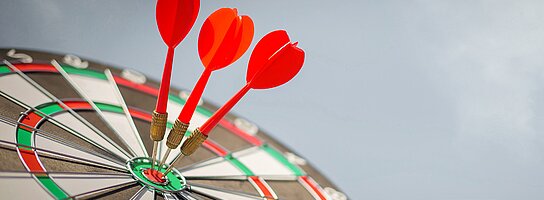 Dartscheibe mit 3 Darts im Zentrum