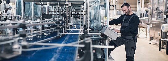 Ein Arbeiter steht in einer Fabrik am Förderband