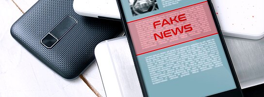 Auf einem Handybildschirm steht Fake News in roter Schrift